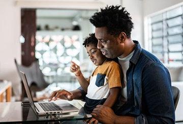 Father and son sitting together at computer